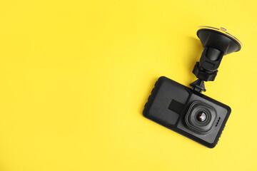 Modern car dashboard camera with suction mount on yellow background, top view. Space for text - obrazy, fototapety, plakaty