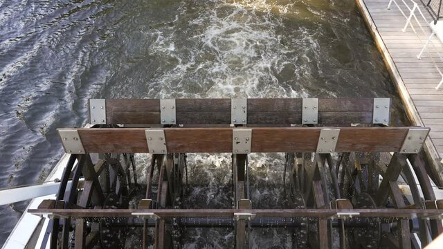 This slow motion video the paddlewheel on the back of a steam boat churning through the water.