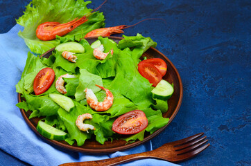 fresh summer salad of vegetables lettuce leaves, cherry tomatoes, cucumber slices and shrimp, seafood dish isolated on a white background