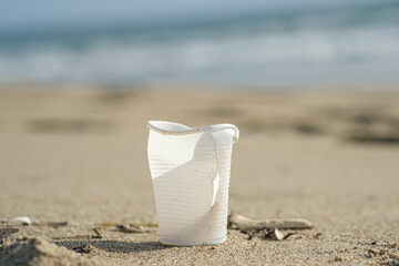 Isolated plastic cup discarded on sea coast ecosystem,nature waste pollution