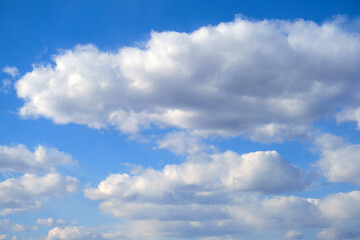 Naklejka na ściany i meble Blue sky background with fluffy soft clouds on a summer day