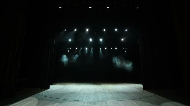 Bright stage lights flashing. Lighting equipment. The lighting designer. Theatrical smoke.