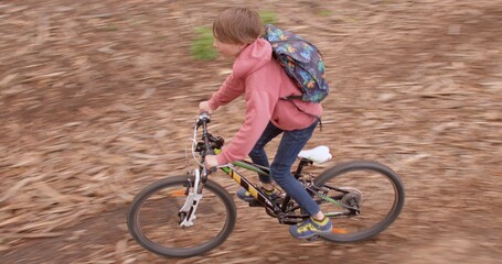 Fototapeta premium A teenager rides a bicycle in the woods. He rolls down a hill along a forest road. Weekend travel. Active lifestyle. Camera movement.