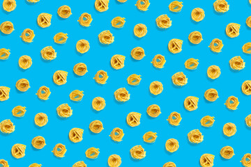 background from Italian tagliatelle pasta. raw pasta fettuccine, pop art background, flat lay. Italian raw nest pasta isolated on blue. not seamless pattern