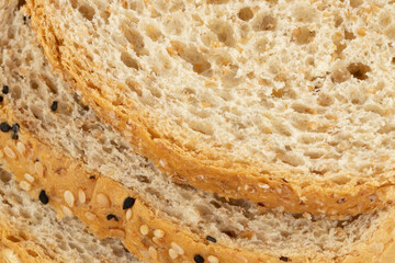 Close up of slices of whole wheat bread with oats, black and white sesame seeds.