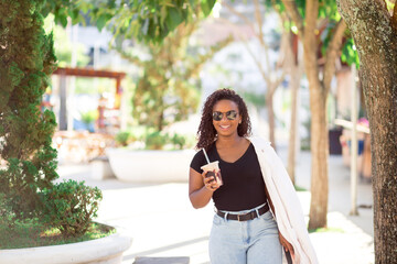 Happy young woman drinking a milkshake on the street.