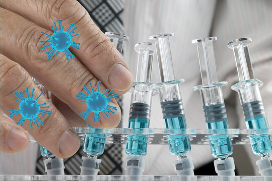 Closed up image of a doctor holding a glass syringe with several other syringes prefilled with blue liquid on a rack. Covid-19 vaccination concepts.