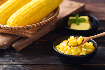 Sweet corn with butter in a bowl eating by spoon on wooden background