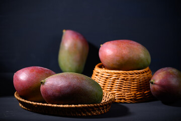 Fresh palmer mango in a basket on black background, Tropical fruit - obrazy, fototapety, plakaty