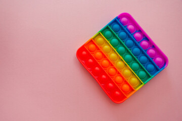 Colorful antistress pop it toy on the pink background.