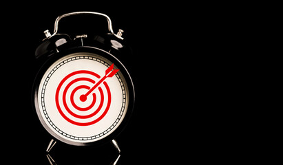Red target board with arrow inside of alarm clock on black background and copy space , time and...
