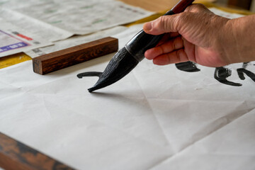 A calligrapher is writing calligraphy characters with a large brush, a close-up of the brush....