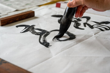 Fototapeta A calligrapher is writing calligraphy characters with a large brush, a close-up of the brush. Translation: The heights are too cold obraz