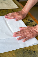 A calligrapher is folding rice paper and writing calligraphy preparations