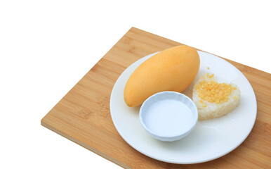 Golden mango and sticky rice served with coconut cream on white circle ceramic plate on bamboo board background. Tropical summer fruit in thailand