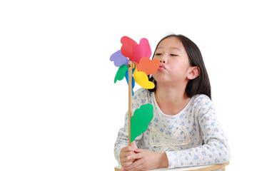 Cute Asian little child girl blowing colorful pinwheel isolated on white background. Kid hold and playing windmill in hand