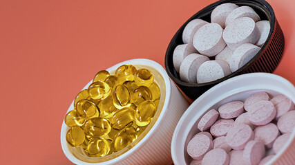 close-up of multivitamin biologically active supplements on coral background. mental wellbeing and personal health concept