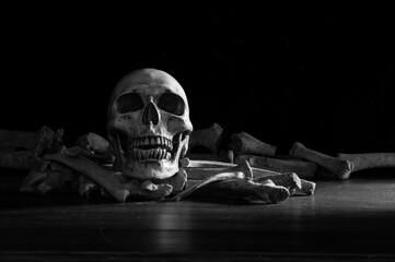 Old skull put on pile of bone on dark ground and black background in morgue