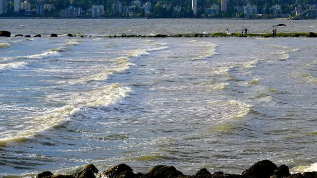 Waves crash over sandstone rock in urban area