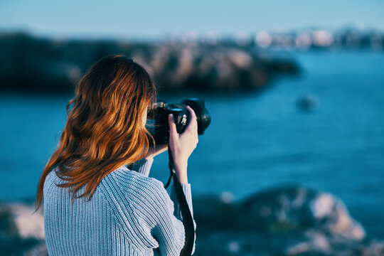 woman taking pictures on camera sea in mountains back view