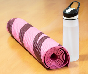 Rolled up yoga mat next water bottle