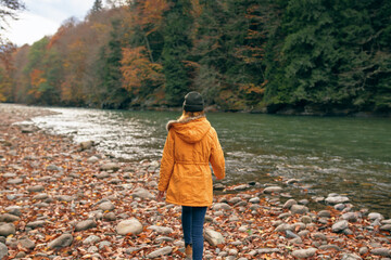 woman walking along the river fallen leaves autumn travel