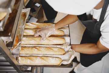 African American baker in uniform sorting baked products on pallets
