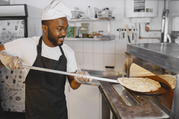 African merican man baking pizza at commercial kitchen