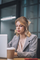 Beautiful young woman at table with coffee and laptop