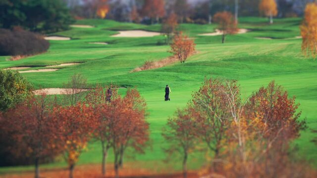 Golf players, who look like characters of Charlie Chaplin movie era, are stepping on the field, setting their equipment, getting ready, and pondering over a stroke, then moving on to the next spot.