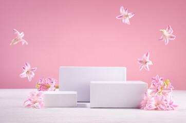Set of tree white podiums for presentation cosmetics produce with  flying fresh spring flowers  on...