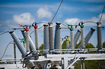 High voltage ceramic insulators on a transformer, against a blue sky with white clouds.