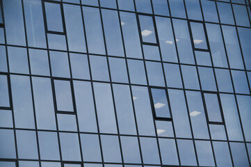 The glass facade of an office building inside the ceiling lights are on.