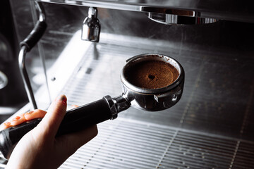 Fototapeta na wymiar Barista pressing ground coffee into portafilter by tamper.