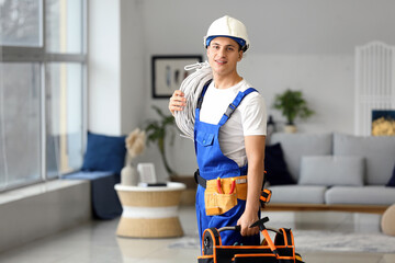 Young electrician with tools in room