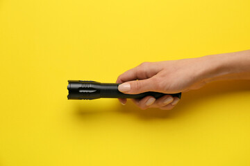Female hand with modern flashlight on color background