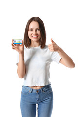 Obraz premium Young woman with covid-19 vaccination card showing thumb-up on white background