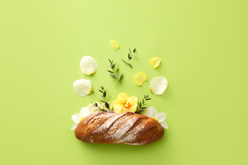 Creative composition with tasty fresh bread and flowers on color background