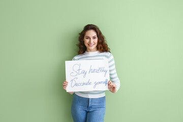 Fototapeta na wymiar Young woman holding poster with text STAY HEALTHY - VACCINATE YOURSELF on color background