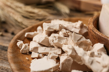 Plate with fresh yeast on wooden background