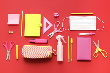 Pencil case with stationery and medical mask on color background