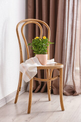 Beautiful yellow roses in pot on chair near window