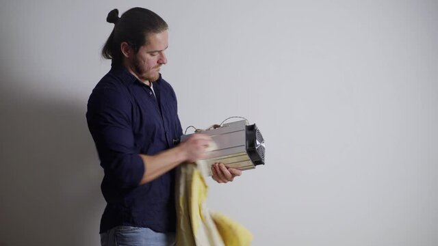 A guy cleans an ASIC for mining on a white background, jokes and smiles