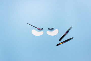 Artificial eyelashes, patches and tweezers on a blue background, top view. The concept of the lashmaker, artificial eyelash extension.