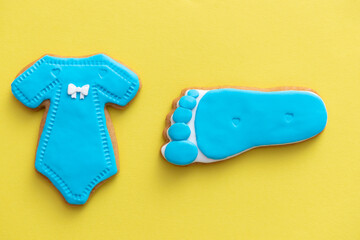 baby body suit and foot made by gingerbread and blue sugar paste on yellow background