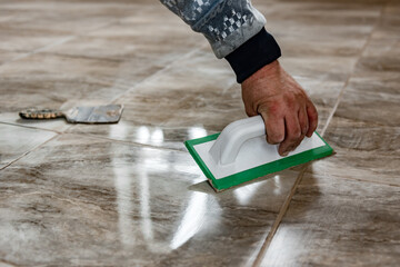 Grouting ceramic tiles. Tilers filling the space between tiles using a rubber trowel.