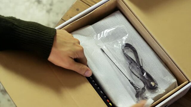 Man Unpacking a Receiver for Satellite and Remote Control at Home. Closeup. 4K Resolution.