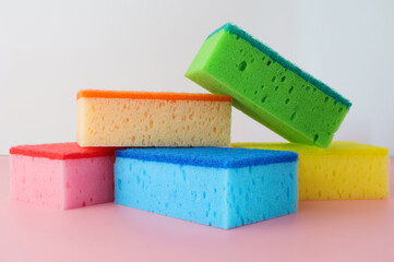 Colorful sponges for dishwashing on pink background.