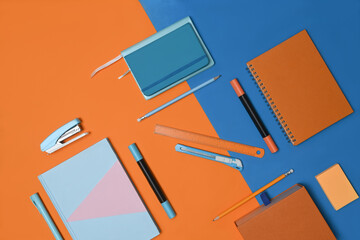 Notebook and stationery on two tone blue and orange background.