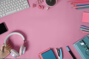 Top view headphone, notebooks and stationery and smart phone on pink background.